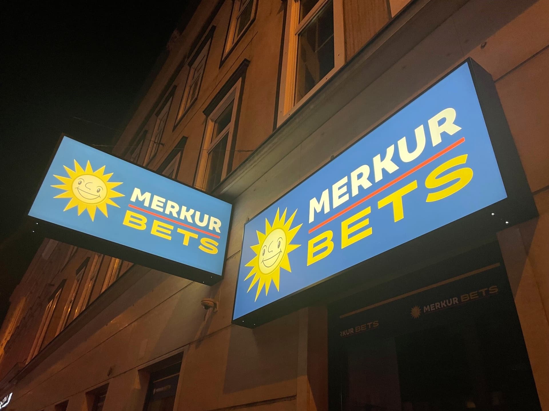 Doppelseitiger Leuchtkasten als Ausleger an einer Fassade, von beiden Seiten sichtbar