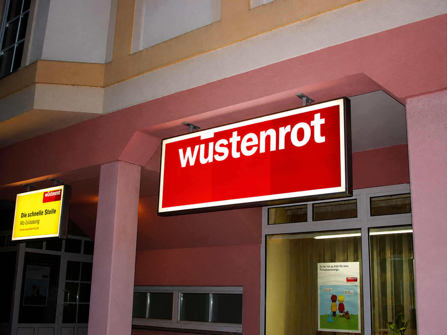 Roter Wüstenrot Leuchtkasten an einer Fassade bei Dämmerung