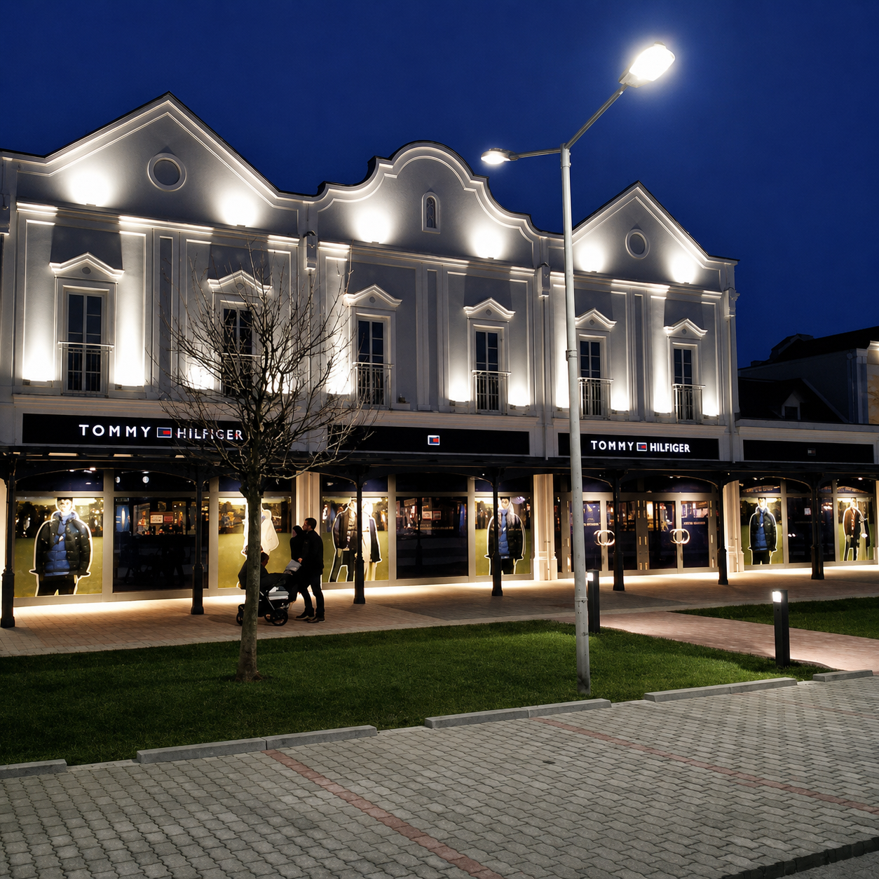 Beleuchtete Fassade des Tommy Hilfiger Shops im Outlet Center bei Nacht