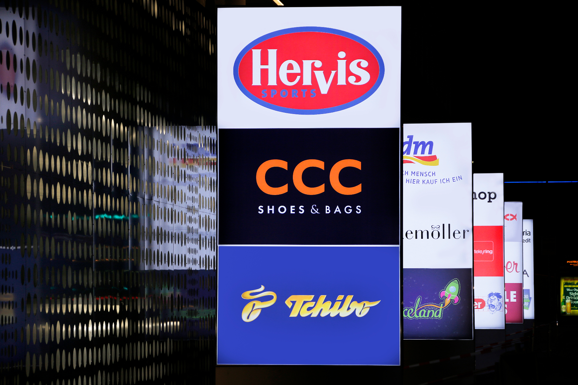 Beleuchtete Pylone mit Markenlogos Hervis, CCC und Tchibo bei Nacht