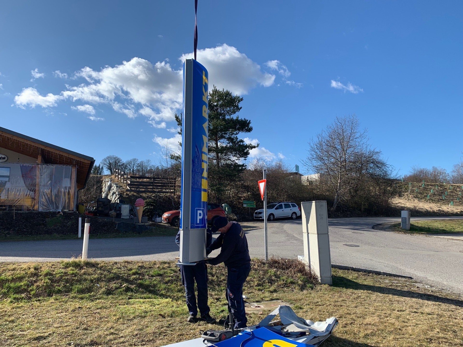 KLW Monteure setzen den neuen Unimarkt Werbepylon mit Kran auf das vorbereitete Fundament