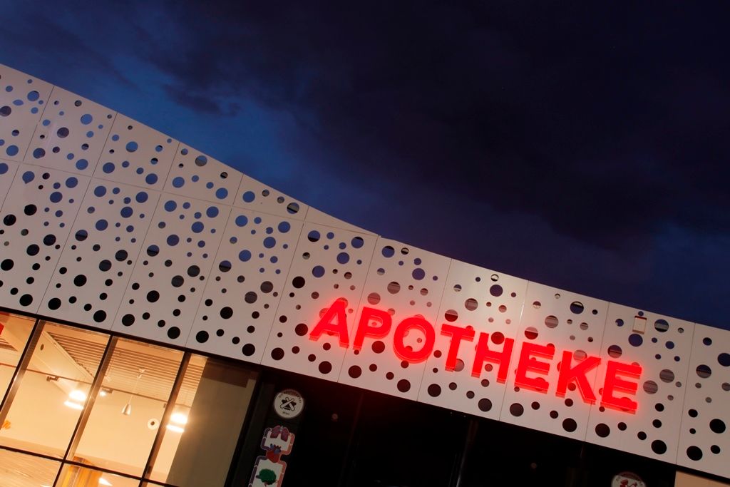 APOTHEKE Einzelbuchstaben rot leuchtend bei Nacht