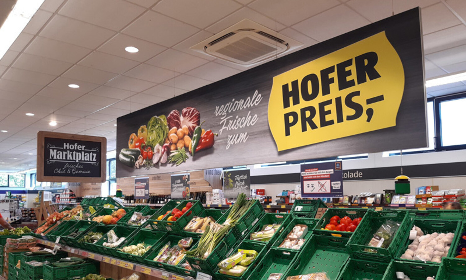 Textilspannrahmen Hofer – beleuchtetes Werbeschild über der Obst- und Gemüseabteilung