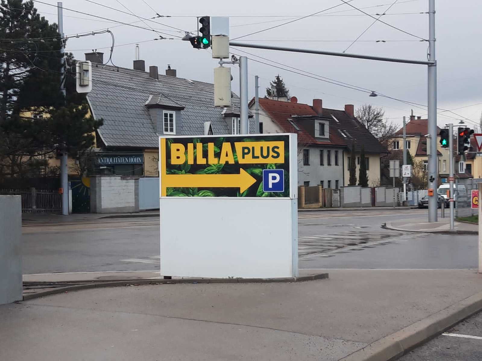 BILLA Plus – Pylon mit Parkplatzhinweis an einer Kreuzung in Wien