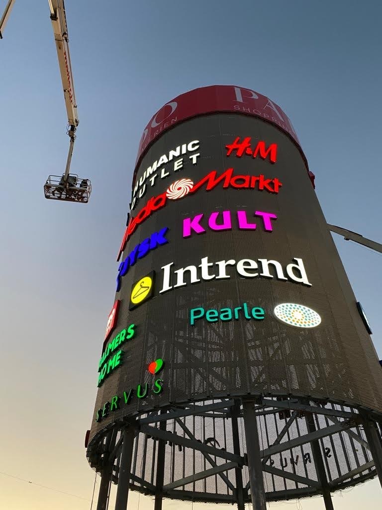 PADO Werbeturm bei Dämmerung mit beleuchteten Mieter-Logos